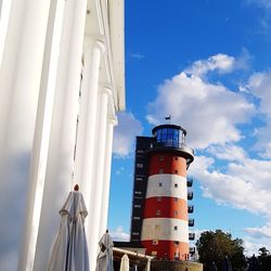 Low angle view of lighthouse by building against sky