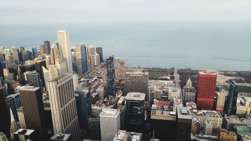 Modern cityscape by sea against sky