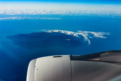 Airplane flying over sea against blue sky