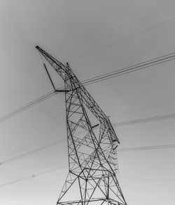 Low angle view of silhouette electricity pylon against sky