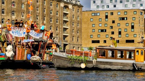 People in canal against buildings in city