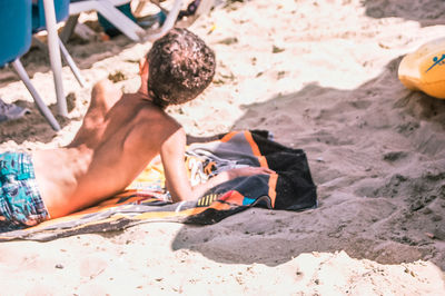 High angle view of man relaxing on sand at beach