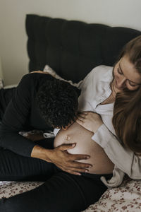 Man kissing pregnant girlfriend's belly