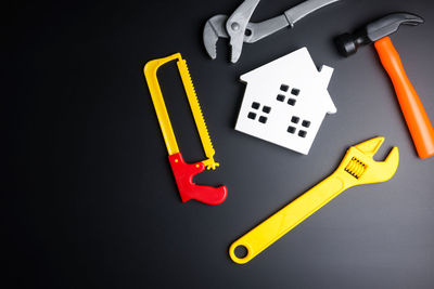 Directly above shot of plastic tools with model house on black background