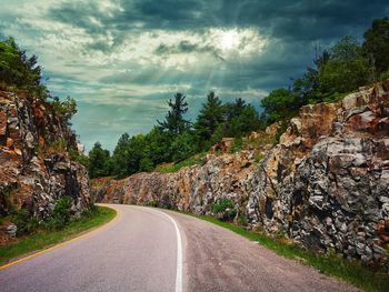 Road amidst trees and plants against sky