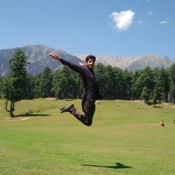 Full length portrait of man jumping on field against sky