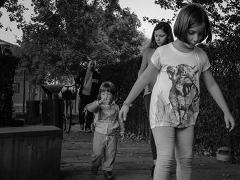 Full length portrait of happy friends standing against trees