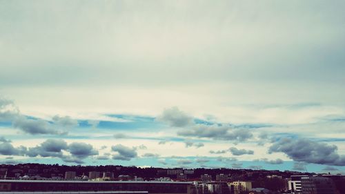 View of cityscape against cloudy sky