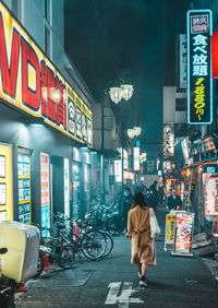Rear view of people walking on illuminated city street