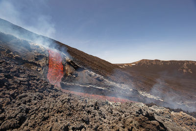 Incandescent lava flow  on the etna volcano in sicily in valle del bove with smoke and flow canal