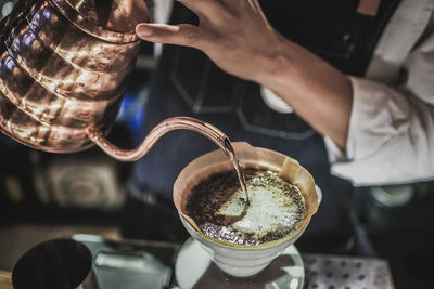 Close-up of hand pouring coffee in cup