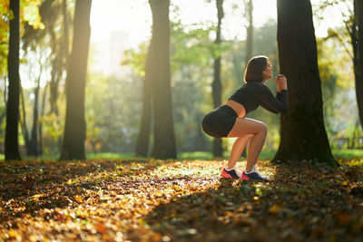 Woman running on road amidst trees in forest