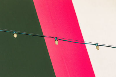 Low angle view of clothespins hanging on rope against sky