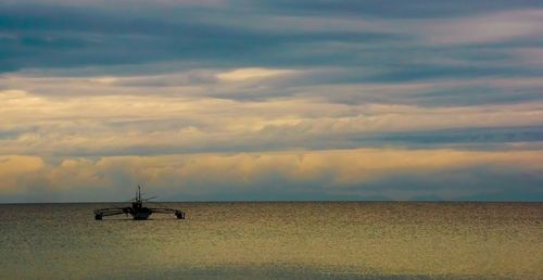 Scenic view of sea against cloudy sky at sunset