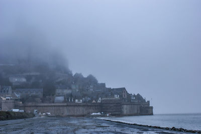 Buildings by sea against sky during winter