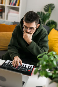 Side view of young man using laptop at home