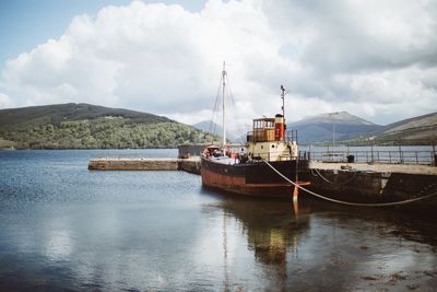 Ship moored at harbor against sky