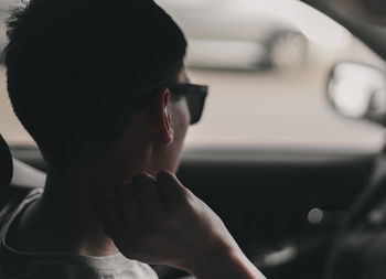 Portrait of a young driver guy looking in the rearview mirror.