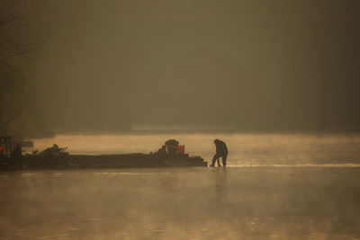 Silhouette people on sea against sky