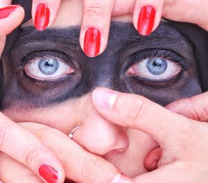 Cropped hands covering woman face with paint