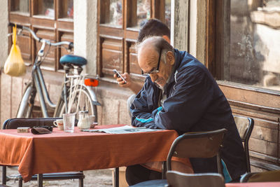Man reading newspaper while sitting at cafe