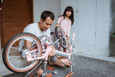 Father repairing bicycle with daughter at home