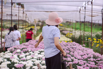 Rear view of woman standing in greenhouse