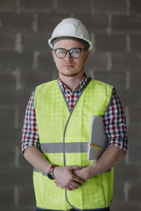 Portrait of young man standing against building
