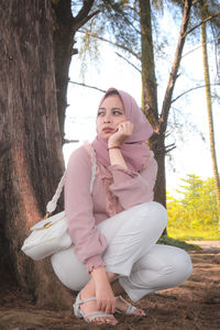 Young woman sitting on tree trunk