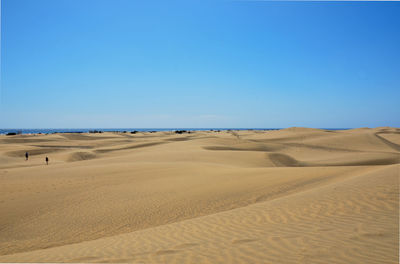 Scenic view of desert against clear blue sky