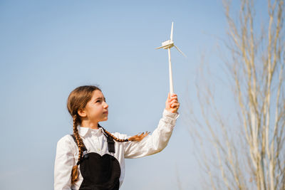 Side view of woman holding umbrella against sky