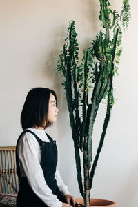 Side view of woman standing against wall