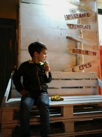 Cute boy looking away while holding ice cream at night