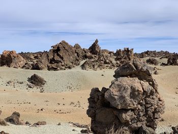 Rock formation on beach against sky