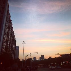 Road in city against sky at sunset