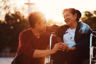 Smiling senior woman with grandson sitting on wheelchair outdoors