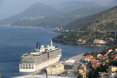 High angle view of city by sea and mountains against sky