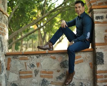 Portrait of smiling man sitting on wall