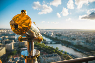 Coin-operated binoculars against sky in city