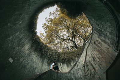 Low angle view of woman standing by wall