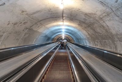 Rear view of people walking on escalator