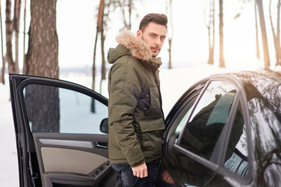 Man standing in car during winter