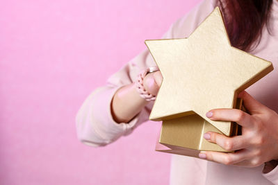 Midsection of person holding book against pink background