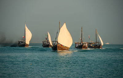 Sailboats sailing in sea against clear sky