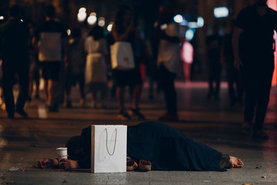 People sitting on street in city at night