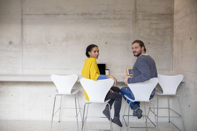 Young man and woman using moblie devices in concrete room