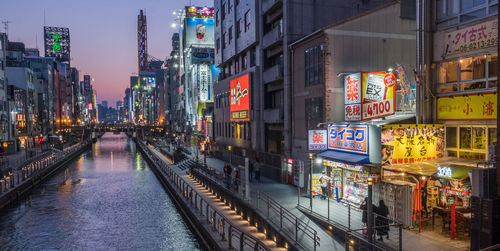 Illuminated street amidst buildings in city at night