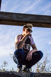 Full length of young man sitting against sky