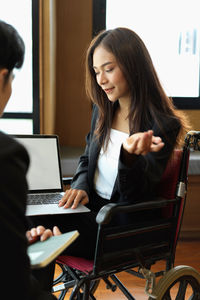 Young woman using phone while sitting on table