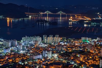 High angle view of illuminated city by buildings at night